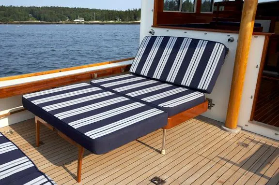 Slide: The Image of Striped cushioned seating on a 2005 John Williams Custom 38 boat deck by the water. - 11