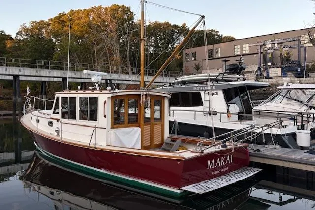 Slide: The Image of 2005 John Williams Custom 38 boat docked, red hull, named "MAKAI," surrounded by trees and buildings. - 22