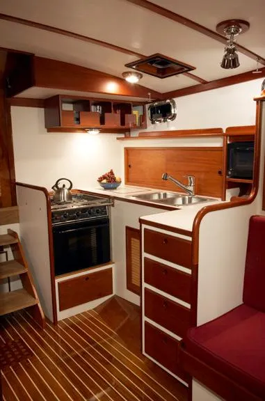 Slide: The Image of Compact yacht kitchen with wooden cabinetry, stainless steel sink, and stove. John Williams Custom 38, 2005. - 7