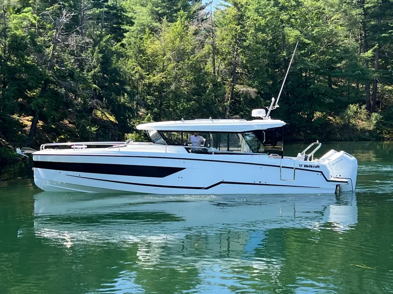 The Image of 2024 Wellcraft 355 Commuter boat on a serene lake surrounded by lush trees. - 0