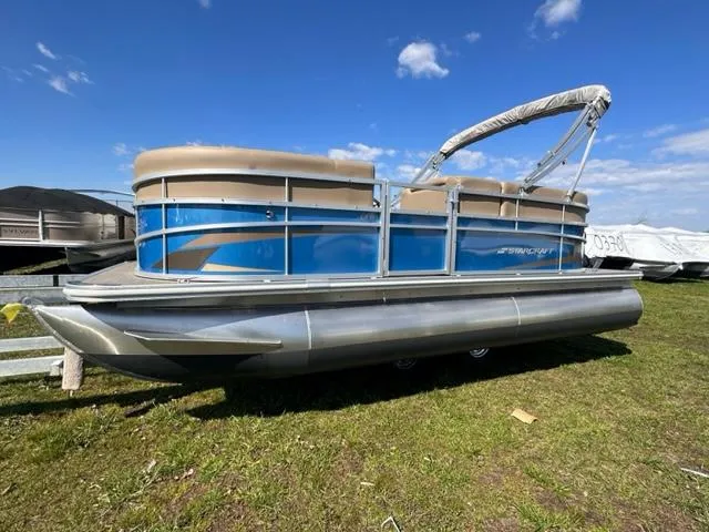 Slide: The Image of 2023 Starcraft LX 18 R pontoon boat on grass under a blue sky. - 0