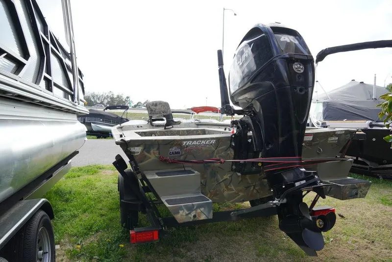 Slide: The Image of 2020 Tracker 1654 Sportsman boat with outboard motor, parked on grass. - 4