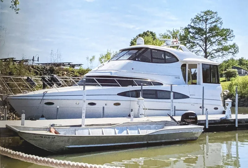 Slide: The Image of 2000 Carver 506 Motor Yacht docked beside a smaller boat on a sunny day. - 0