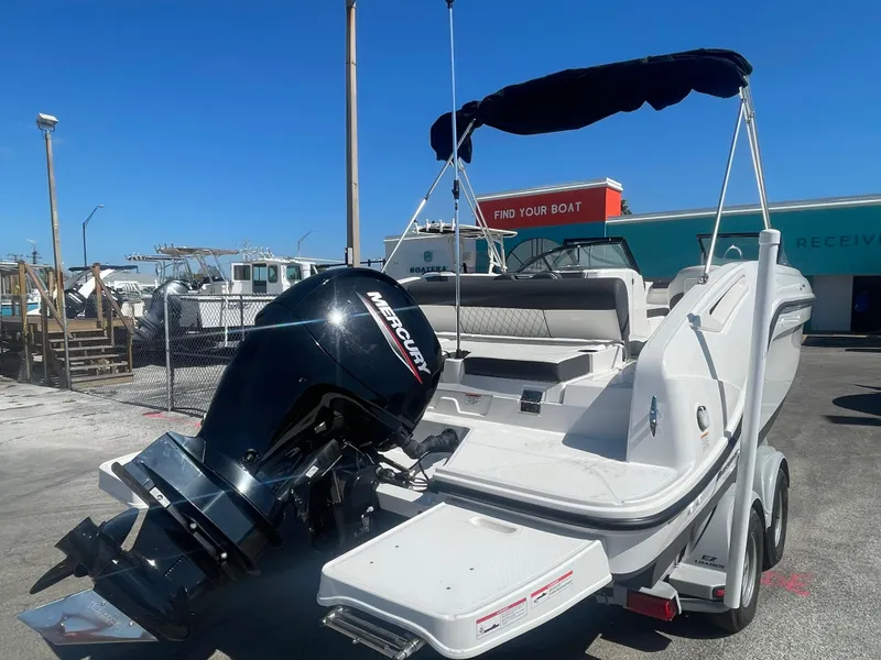 Slide: The Image of 2021 Bayliner DX 2200 boat with Mercury outboard motor in a marina. - 2