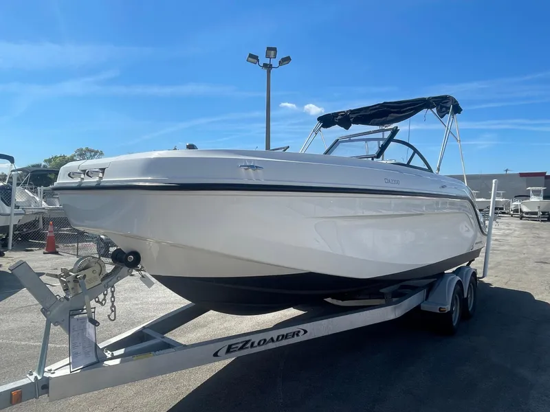 Slide: The Image of 2021 Bayliner DX 2200 boat on EZ Loader trailer under clear blue sky. - 4