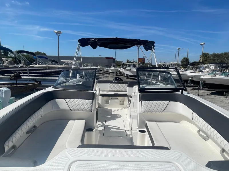 Slide: The Image of 2021 Bayliner DX 2200 boat with open deck and seating, docked at a marina. - 6