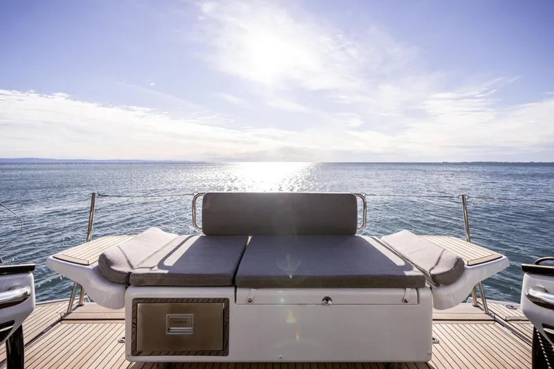 Slide: The Image of 2024 Jeanneau 65 yacht deck with sunbed, overlooking serene ocean view. - 18