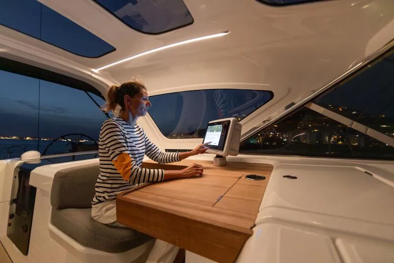 Slide: The Image of Woman navigating on 2024 Jeanneau Yacht 55 at night, using onboard technology. - 25
