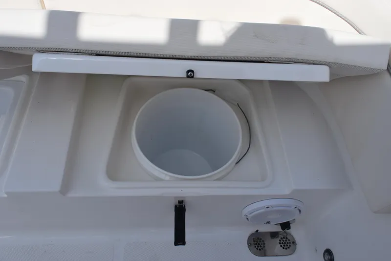 Slide: The Image of 2024 Sea Hunt Escape 25 boat storage compartment with open lid and circular container. - 25