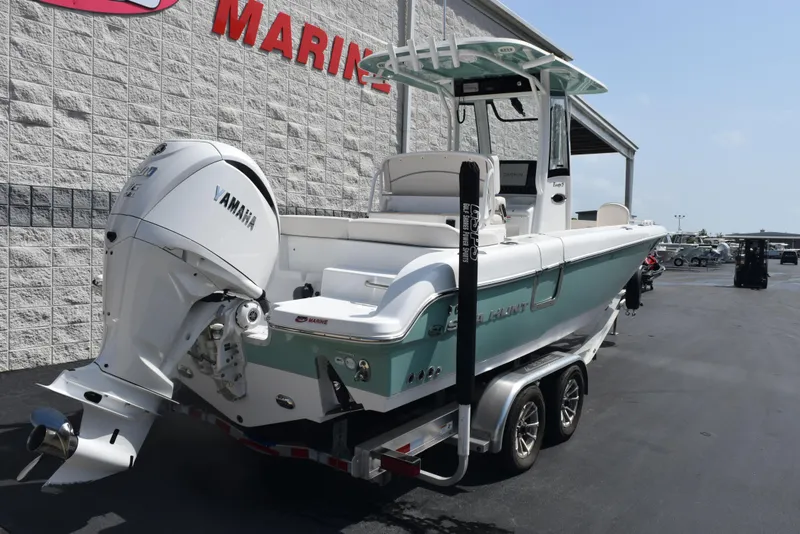 Slide: The Image of 2024 Sea Hunt Escape 25 boat with Yamaha engine on trailer, parked outside marine store. - 4