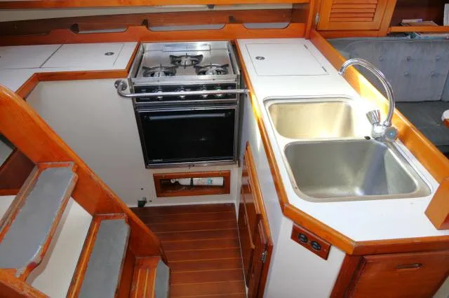 Slide: The Image of Catalina 36 1991 yacht kitchen with stove, sink, and wooden cabinetry. - 13