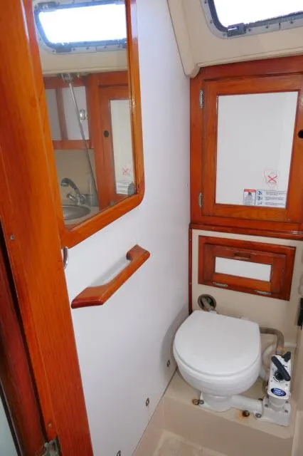 Slide: The Image of 1991 Catalina 36 sailboat bathroom with wooden cabinets and a marine toilet. - 31