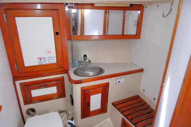 Slide: The Image of 1991 Catalina 36 sailboat bathroom with wooden cabinets, sink, and toilet. - 32