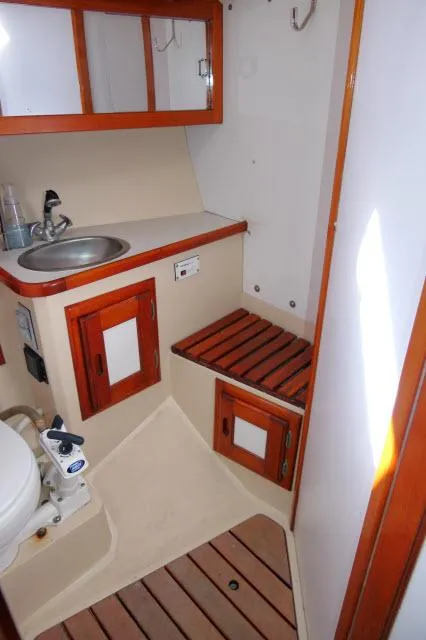 Slide: The Image of 1991 Catalina 36 sailboat bathroom with sink, toilet, and wooden storage cabinets. - 33