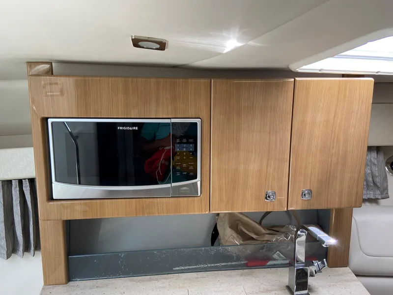 Slide: The Image of 2017 Formula 350 Sun Sport boat interior kitchen with microwave and wooden cabinets. - 32
