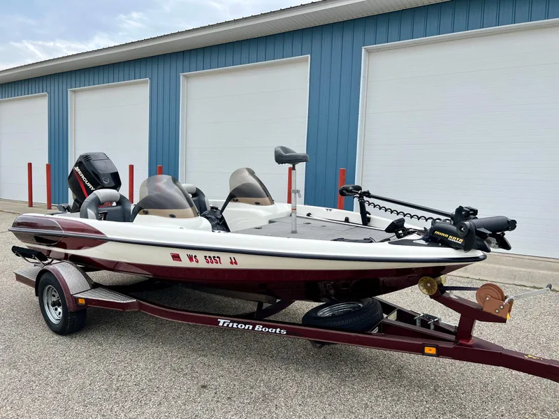 Slide: The Image of 2000 Triton TR170C fishing boat on trailer, parked outside blue storage units. - 2
