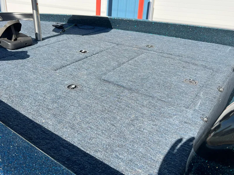 Slide: The Image of 2000 Triton TR170C boat deck with blue carpet and storage compartments. - 7