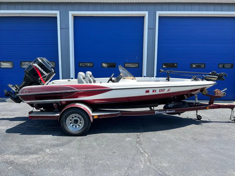 Slide: The Image of 2000 Triton TR170C boat with trailer, parked in front of blue garage doors. - 8