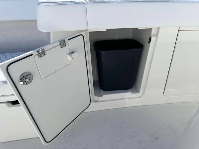 Slide: The Image of Open storage compartment with a black bin on a 2024 Solace 37 CS boat. - 31