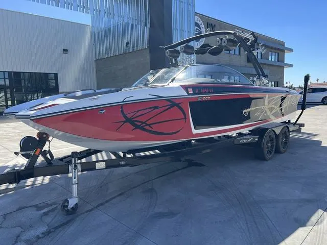 Slide: The Image of 2014 Tigé RZ4 boat on trailer, red and black design, parked outside modern building. - 2