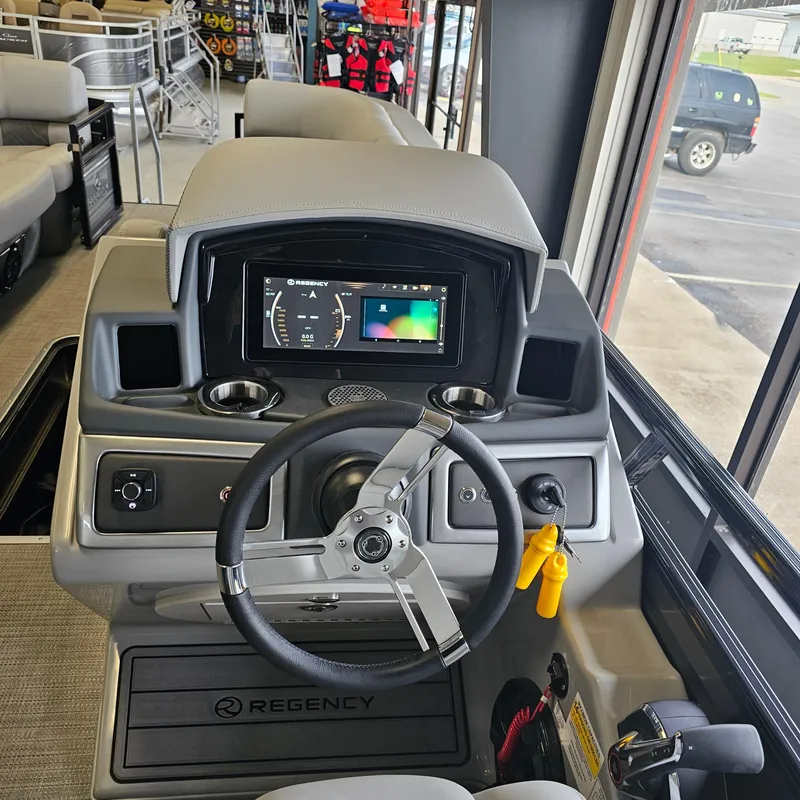 Slide: The Image of 2024 Regency 250 LE3 Sport boat dashboard with steering wheel and digital display. - 15