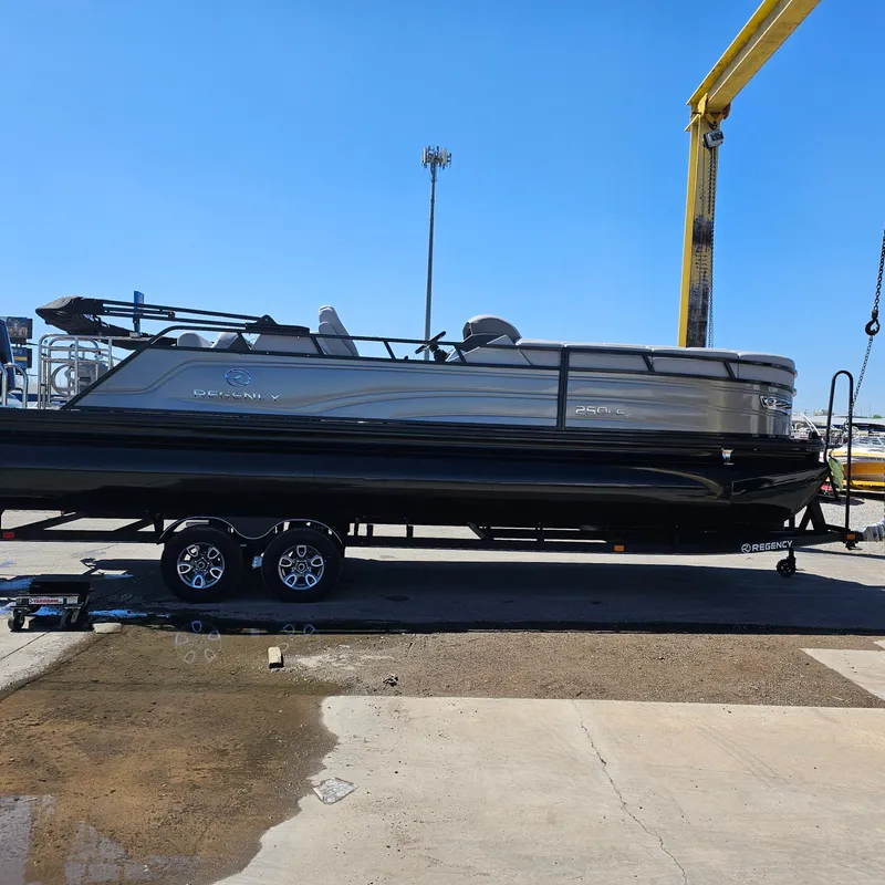 Slide: The Image of 2024 Regency 250 LE3 Sport pontoon boat on a trailer at a dock. - 2