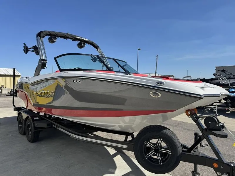 Slide: The Image of 2024 MasterCraft NXT 22 boat on trailer under clear blue sky. - 1