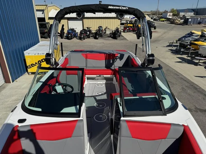Slide: The Image of 2024 MasterCraft NXT 22 boat with red and gray interior at a dealership. - 16