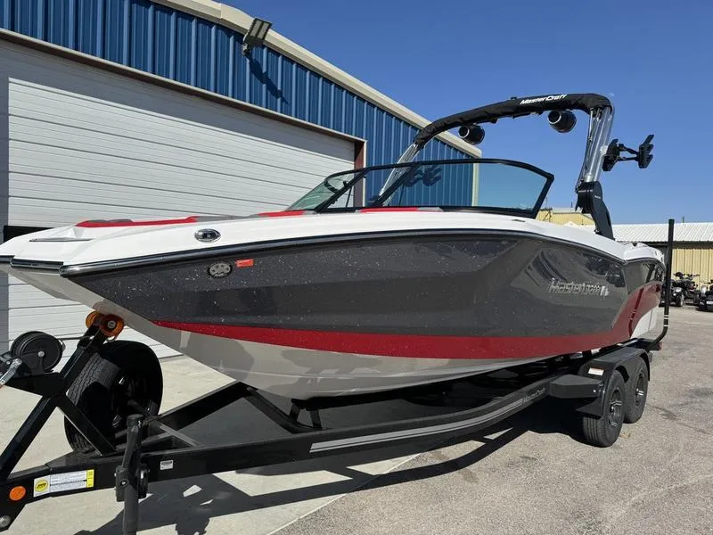 Slide: The Image of 2024 MasterCraft NXT 22 boat on trailer outside a blue warehouse. - 2