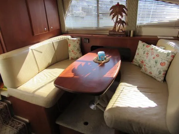 Slide: The Image of Interior seating area of a 2004 Silverton 330 Sport Bridge yacht with a wooden table. - 13