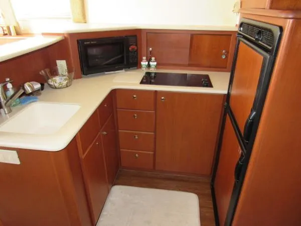 Slide: The Image of 2004 Silverton 330 Sport Bridge kitchen with microwave, stove, sink, and refrigerator. - 15