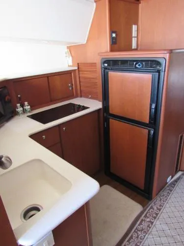 Slide: The Image of 2004 Silverton 330 Sport Bridge kitchen with sink, stove, and refrigerator. - 16