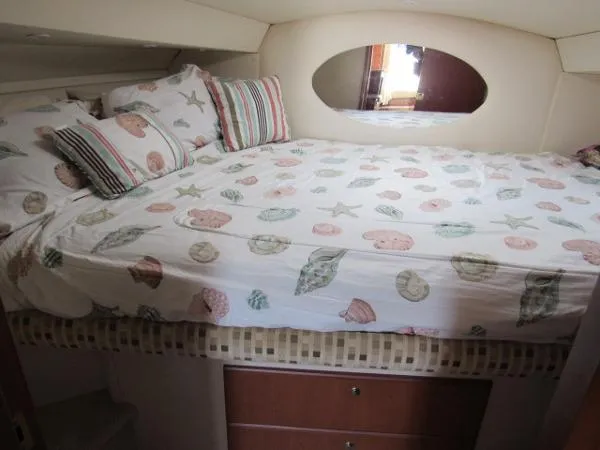 Slide: The Image of 2004 Silverton 330 Sport Bridge bedroom with seashell-themed bedding and oval mirror. - 17