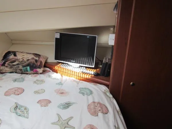 Slide: The Image of 2004 Silverton 330 Sport Bridge cabin with bed, TV, and seashell-themed bedding. - 18