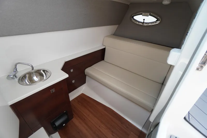 Slide: The Image of 2025 Chaparral 280 OSX cabin interior with sink, seating, and wood flooring. - 27