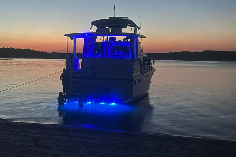 Slide: The Image of 1988 Carver 4207 Aft Cabin yacht with blue lights at sunset on a calm lake. - 2