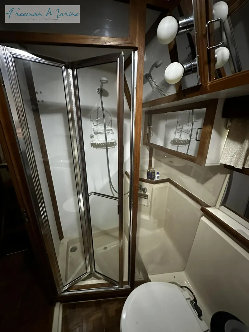 Slide: The Image of 1988 Carver 4207 Aft Cabin bathroom with shower, mirror, and lighting fixtures. - 21