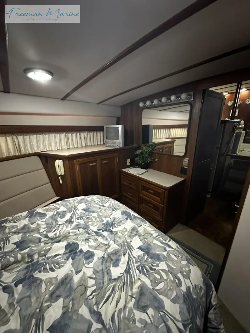 Slide: The Image of 1988 Carver 4207 Aft Cabin interior with bed, TV, and wooden cabinetry. - 23