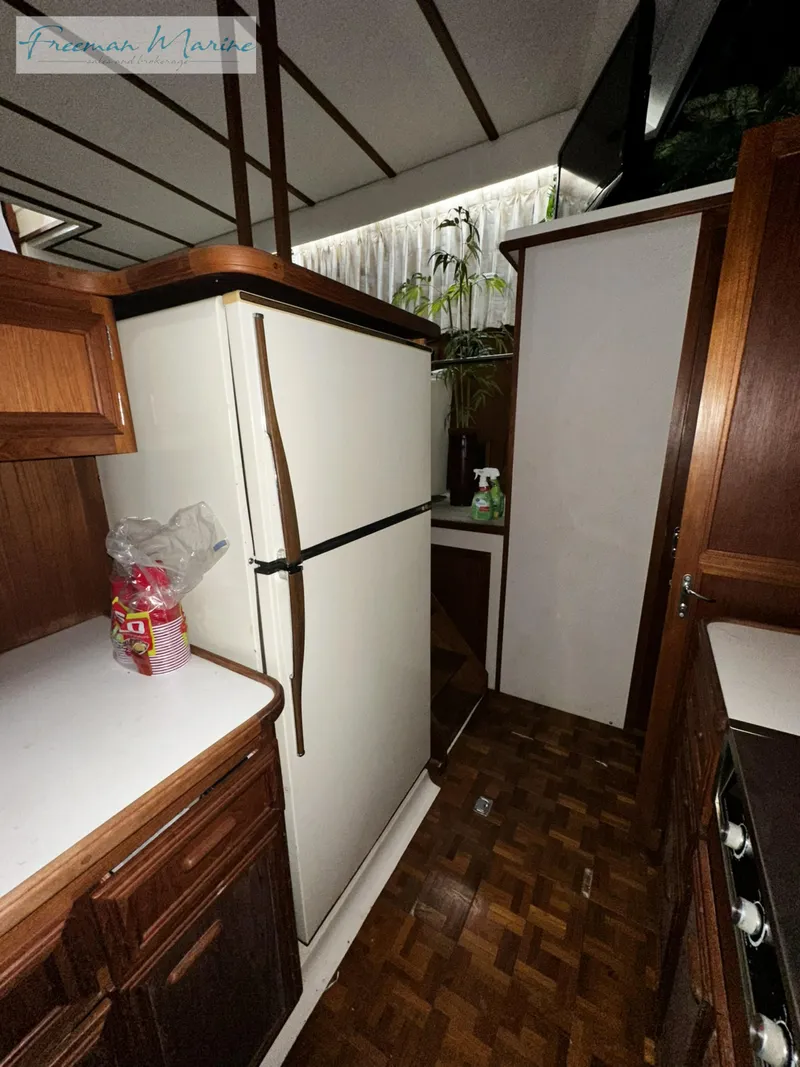 Slide: The Image of 1988 Carver 4207 Aft Cabin kitchen with wood cabinetry and white appliances. - 27