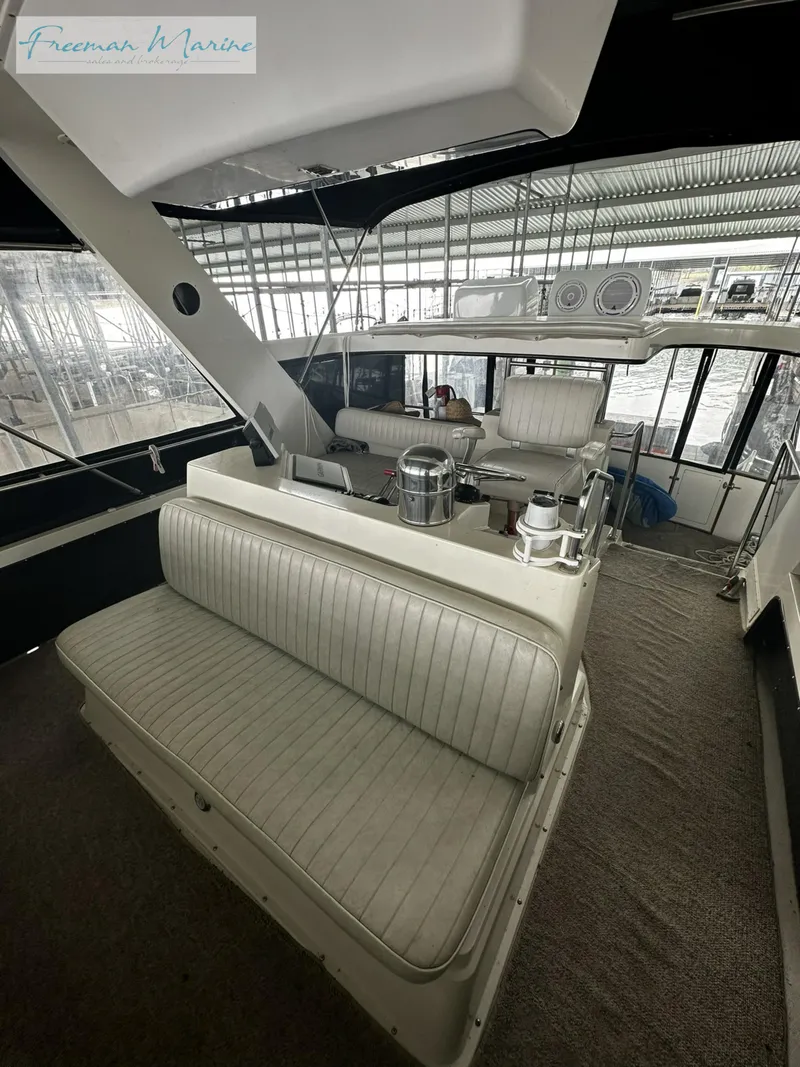 Slide: The Image of 1988 Carver 4207 Aft Cabin interior with seating and helm in marina setting. - 7
