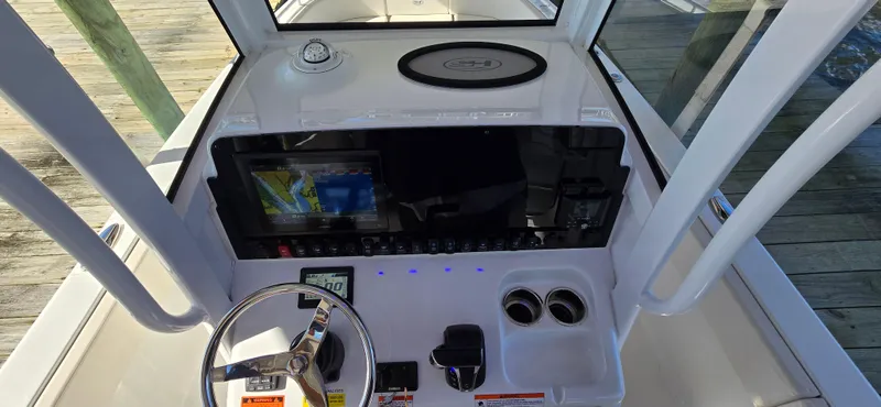 Slide: The Image of 2023 Sea Hunt Escape 250 boat dashboard with steering wheel, navigation system, and cup holders. - 1