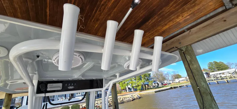 Slide: The Image of 2023 Sea Hunt Escape 250 boat with rod holders and speakers under a wooden dock. - 20