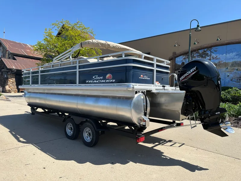 Slide: The Image of 2024 Sun Tracker Fishin' Barge 22 XP3 pontoon boat on trailer with Mercury outboard motor. - 2