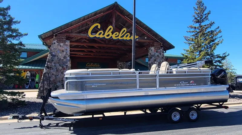 The Image of 2024 Sun Tracker Party Barge 24 DLX pontoon boat displayed outside Cabela's store. - 0
