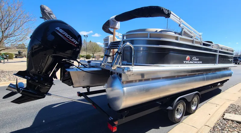 Slide: The Image of 2024 Sun Tracker Party Barge 24 DLX pontoon boat on a trailer with Mercury outboard motor. - 2