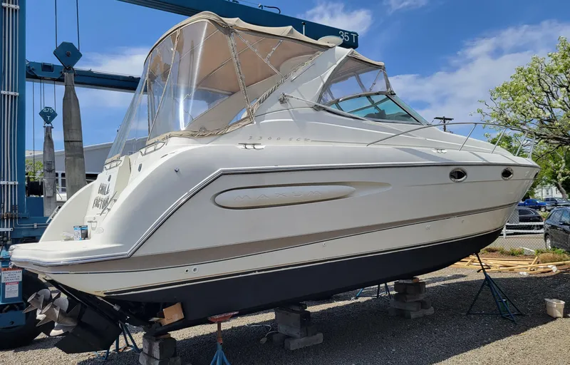 Slide: The Image of 2001 Maxum 3300 SCR boat on dry dock, white exterior, clear sky background. - 2