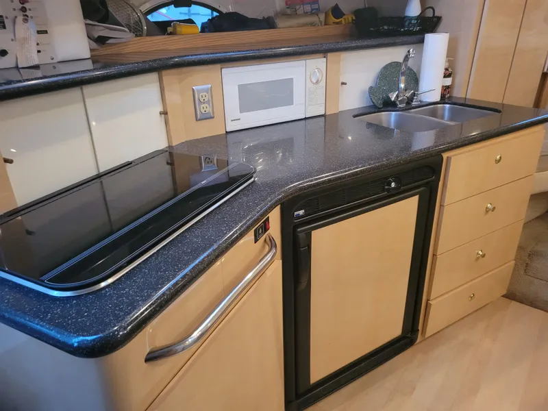 Slide: The Image of 2001 Maxum 3300 SCR yacht kitchen with stove, microwave, sink, and compact fridge. - 6