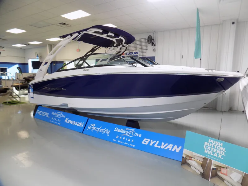Slide: The Image of 2024 Regal LX2 boat displayed indoors with promotional banners. - 0