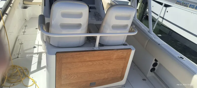 Slide: The Image of 2015 Chris-Craft Catalina 29 boat interior with dual white seats and wooden panel. - 32