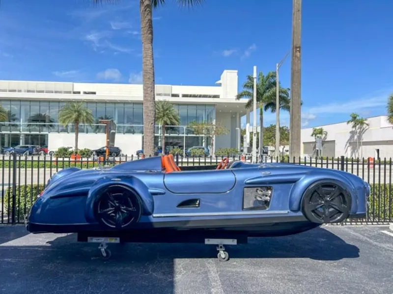 The Image of 2023 Watersports Car Series M, blue, parked outdoors near modern building and palm trees. - 0
